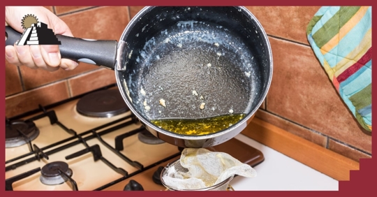 A person tilting a pan with hot oil into a strainer cup