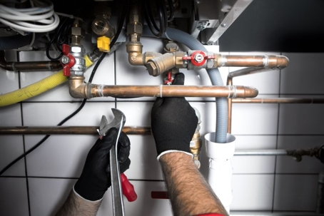 plumber working on repiping under sink