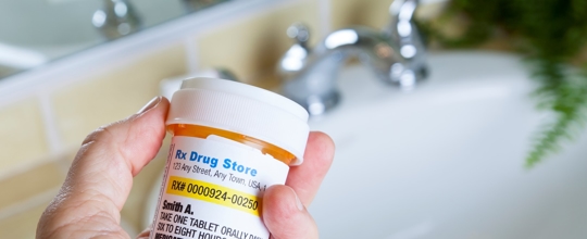 hand dumping medication down sink