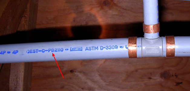 Close up of a polybutylene pipe stamped with the PB2110 text identifying it as polybutylene