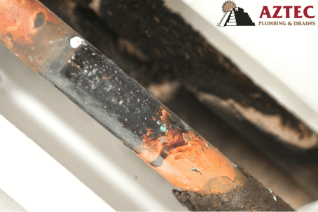 rusty leaking pipe with Aztec Plumbing logo