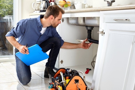 plumber fixing a leaky faucet under sink