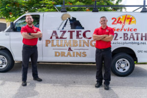 Two Aztec plumbers standing in front of a service van